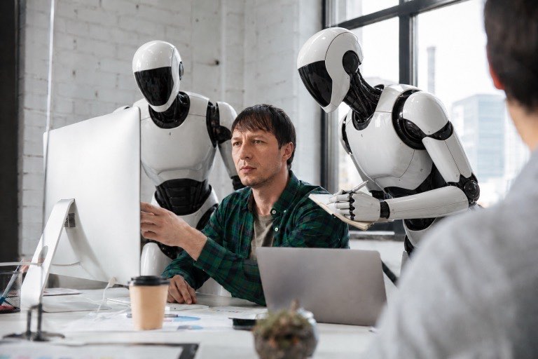 Człowiek i roboty pracują razem przy komputerze w biurze